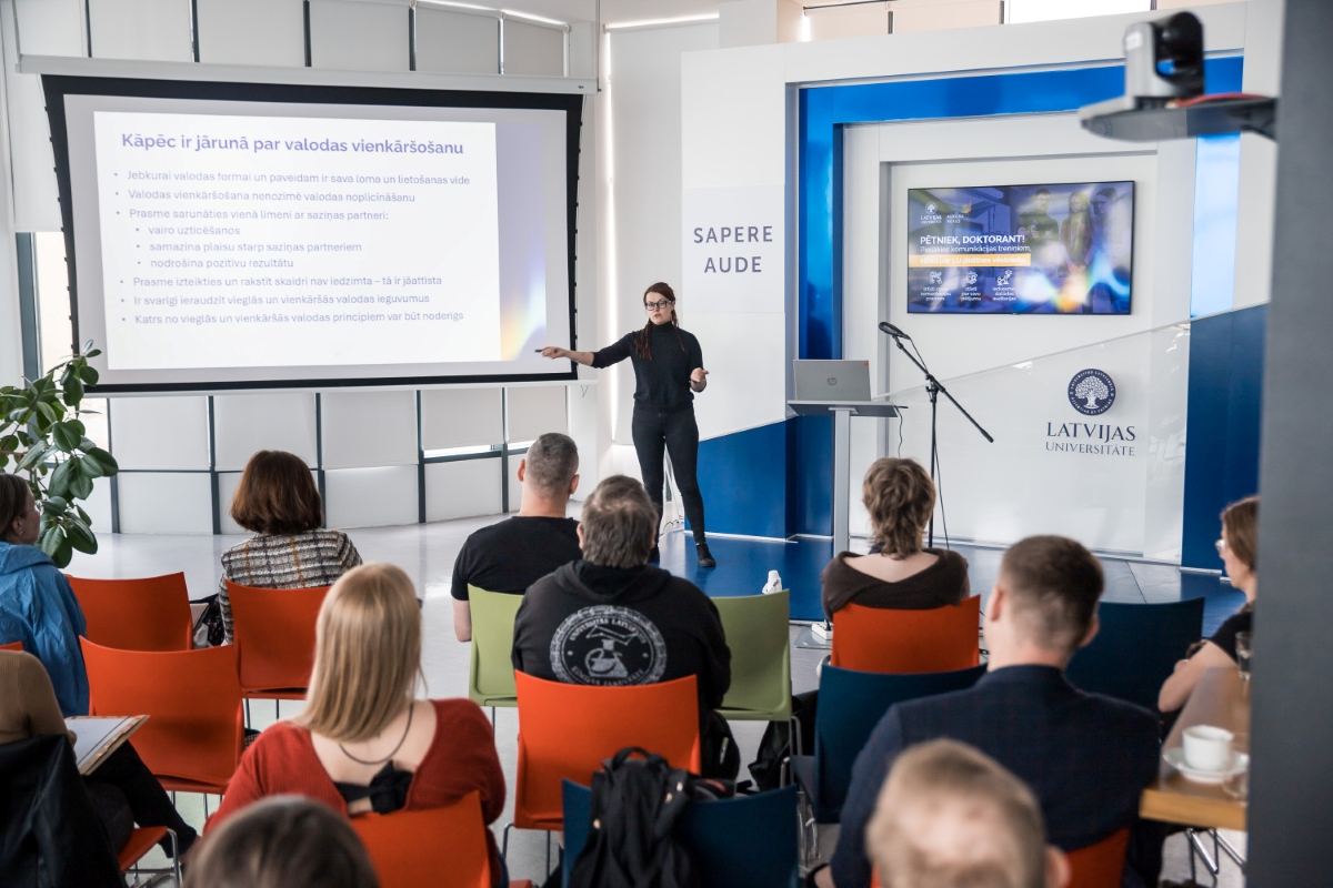 Foto: Toms Grīnbergs, LU Lektore uzstājas auditorijā Latvijas Universitātē, prezentējot tematu par valodas vienkāršošanu