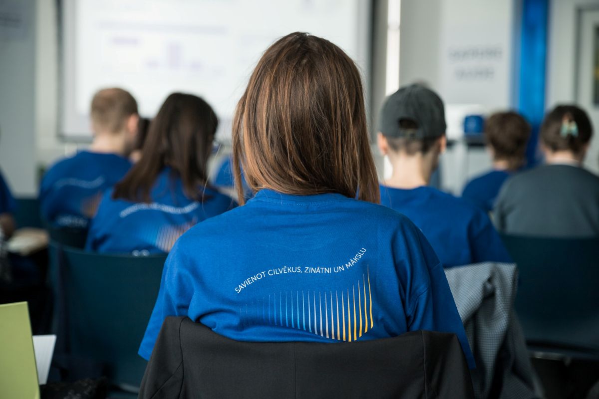 Foto: Toms Grīnbergs, LU Semināra dalībnieki zilos krekliņos klausās prezentāciju Latvijas Universitātes telpās